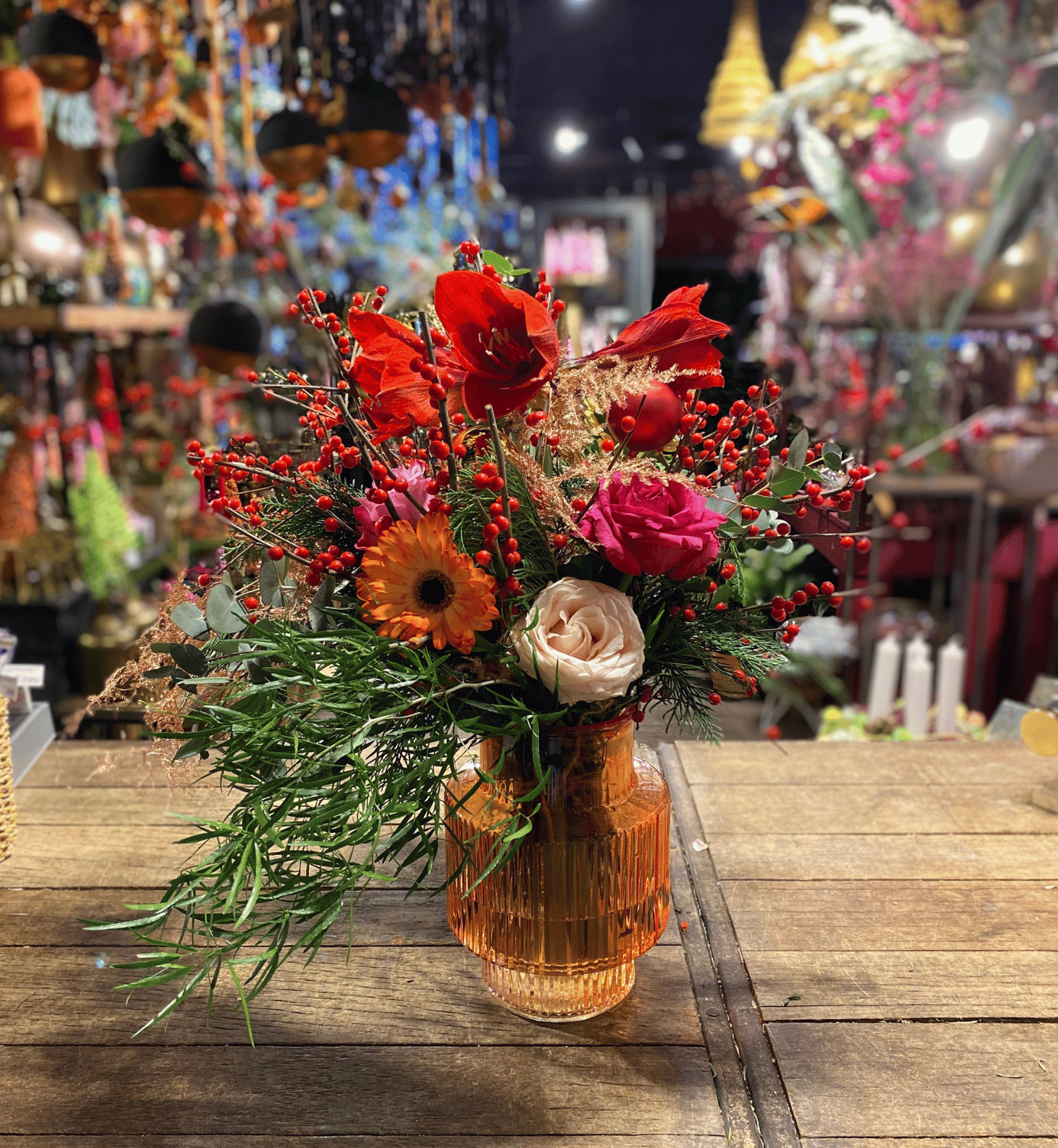 Prachtig kleurrijk boeket met rode en oranje bloemen, blauwe distels en gouden accenten, gepresenteerd in een glazen vaas op een houten tafel. 2