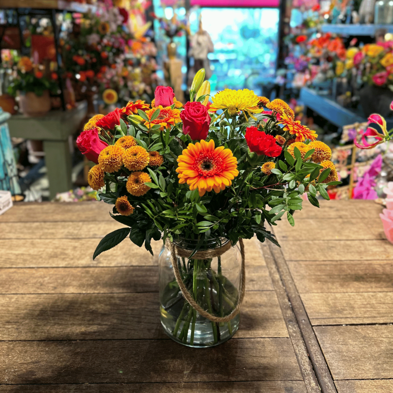 Happy Orange arrangement met een stralende mix van oranje bloemen en natuurlijke accenten.  